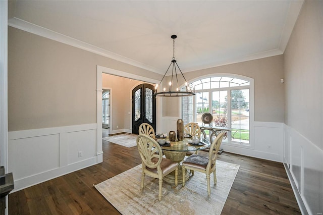 dining space featuring dark wood-type flooring, french doors, ornamental molding, and a chandelier