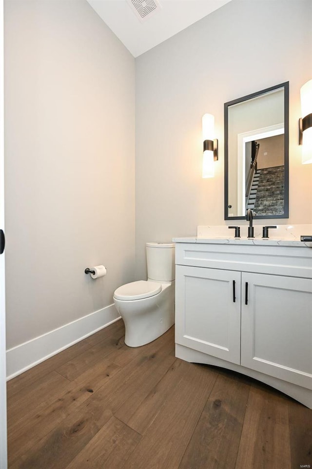 bathroom with toilet, vanity, and hardwood / wood-style floors