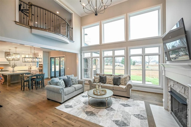 living room with a towering ceiling, light wood-type flooring, and a notable chandelier