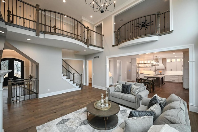 living room featuring a towering ceiling, dark wood-type flooring, french doors, and a notable chandelier