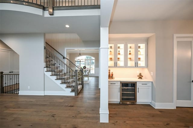 bar with dark wood-type flooring, white cabinetry, decorative light fixtures, and wine cooler