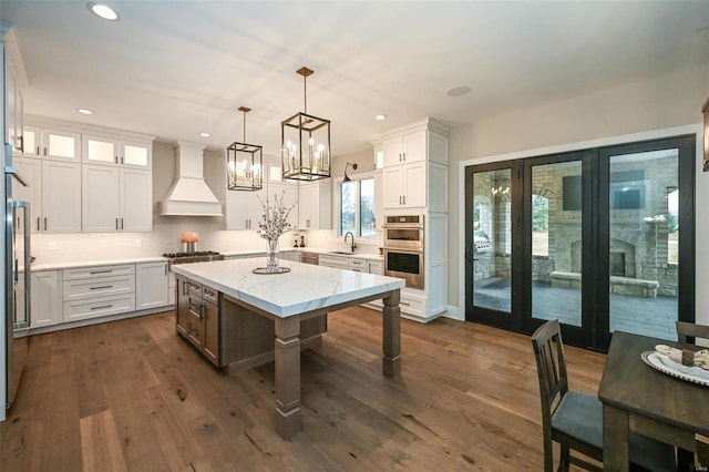 kitchen featuring a kitchen island, white cabinets, and premium range hood