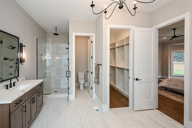 bathroom featuring ceiling fan with notable chandelier, a shower with door, vanity, and toilet