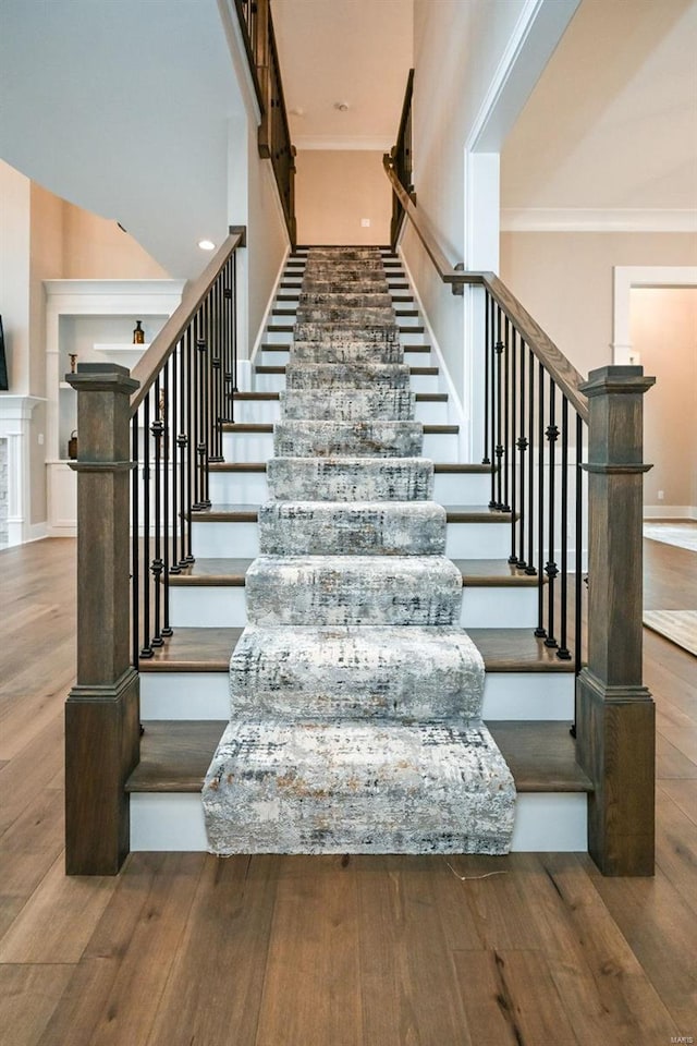 stairway with hardwood / wood-style floors and crown molding