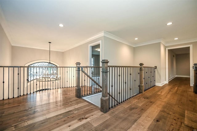 hall with a notable chandelier, crown molding, and wood-type flooring