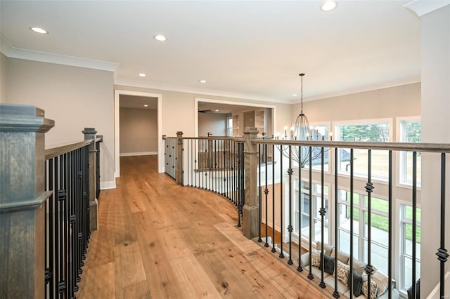 hall featuring a notable chandelier, light hardwood / wood-style floors, and crown molding