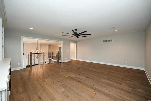 unfurnished living room with ceiling fan with notable chandelier and wood-type flooring