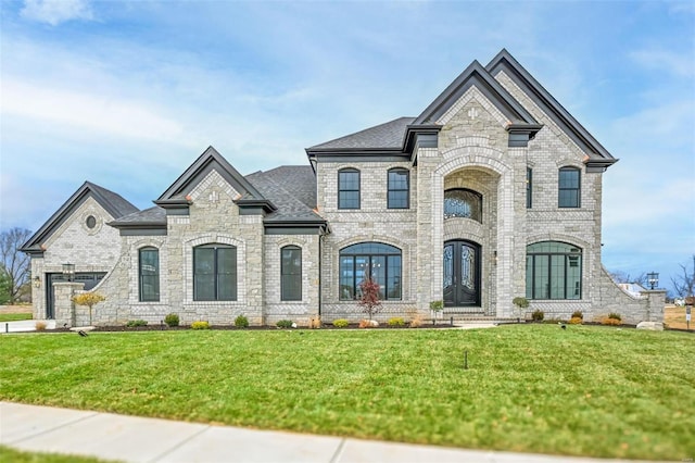 french country home featuring concrete driveway, brick siding, a front lawn, and roof with shingles