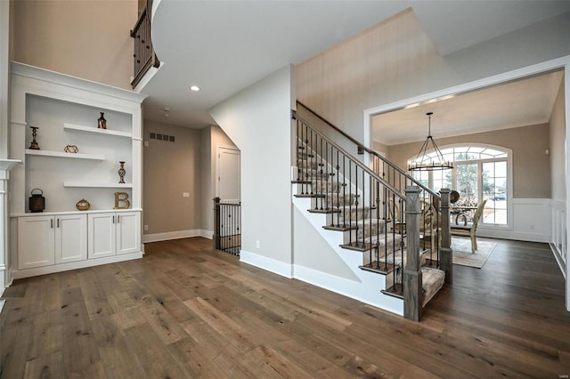 staircase featuring recessed lighting, a wainscoted wall, wood finished floors, visible vents, and an inviting chandelier