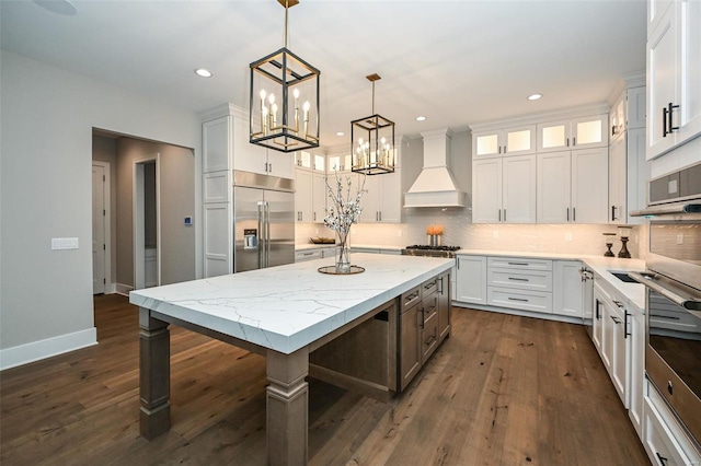 kitchen featuring white cabinets, a kitchen island, hanging light fixtures, custom exhaust hood, and stainless steel appliances