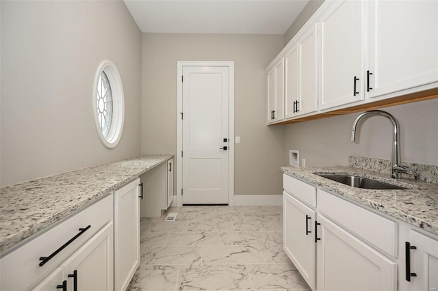 clothes washing area with washer hookup, a sink, baseboards, marble finish floor, and cabinet space