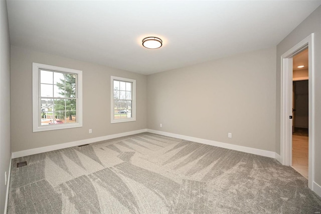 carpeted spare room featuring visible vents and baseboards