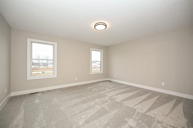 spare room featuring baseboards, visible vents, and carpet flooring