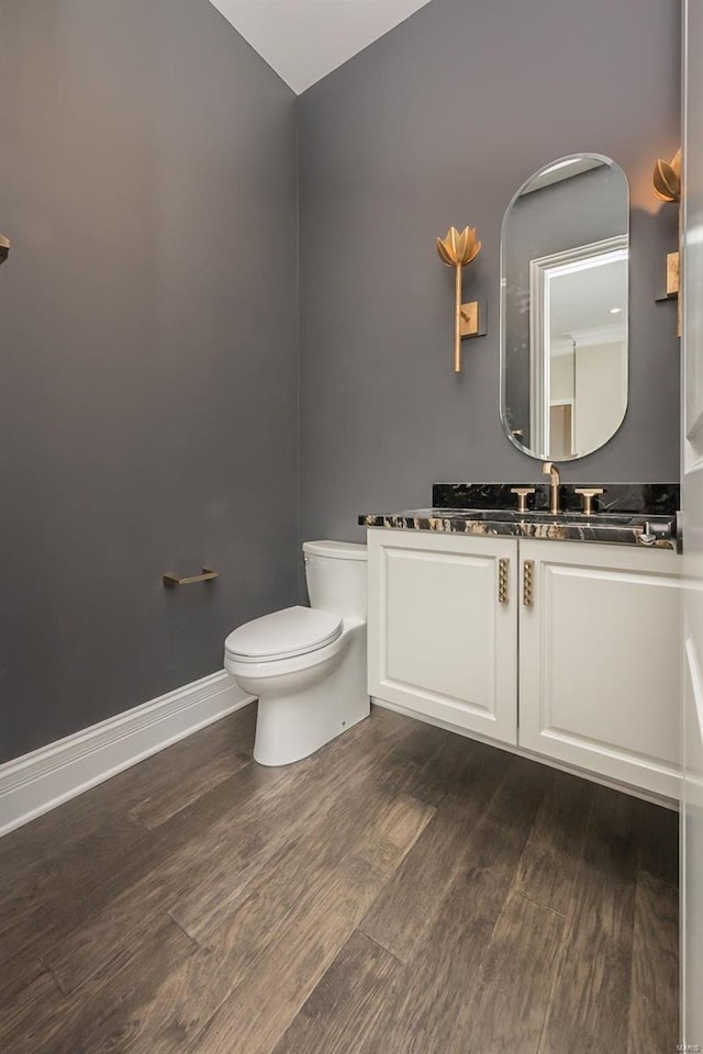 bathroom featuring baseboards, toilet, vaulted ceiling, wood finished floors, and vanity