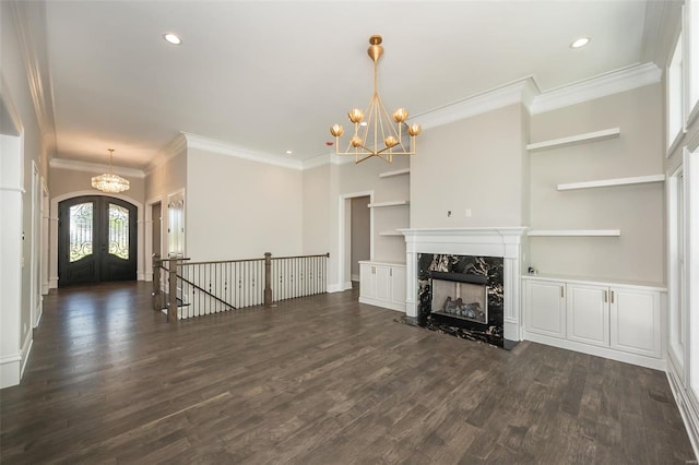 unfurnished living room featuring dark wood-style floors, a premium fireplace, an inviting chandelier, recessed lighting, and french doors