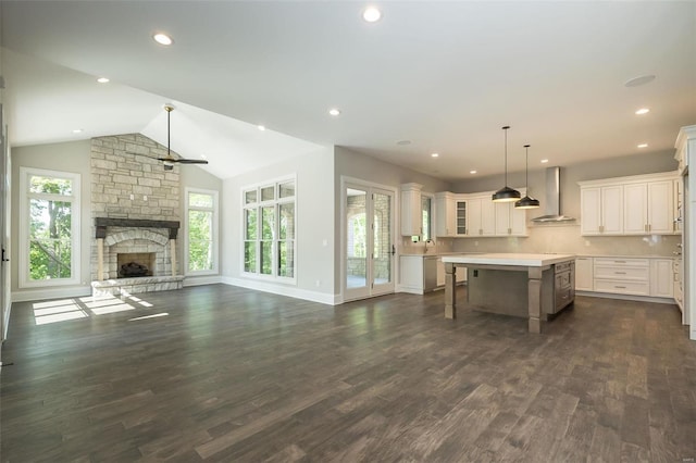 kitchen featuring a center island, dark wood finished floors, open floor plan, a fireplace, and wall chimney exhaust hood