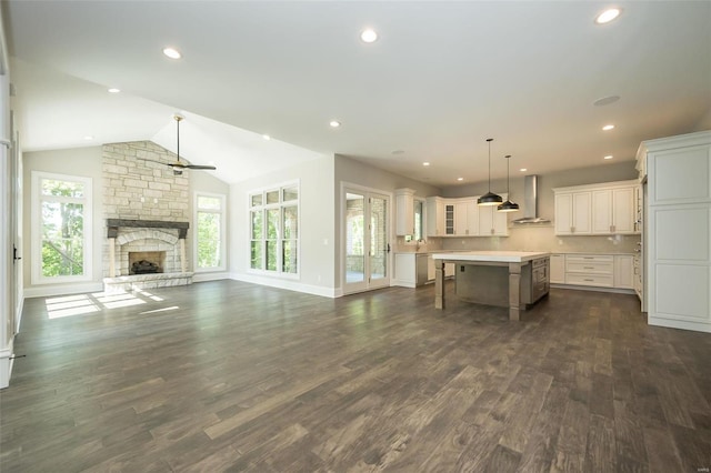 unfurnished living room with recessed lighting, lofted ceiling, a stone fireplace, and dark wood finished floors