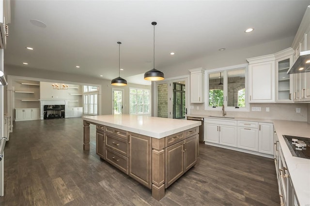 kitchen with white cabinetry, dark wood-type flooring, black stovetop, and a sink