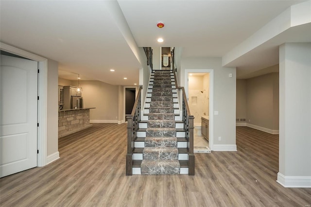 stairs with recessed lighting, wood finished floors, and baseboards