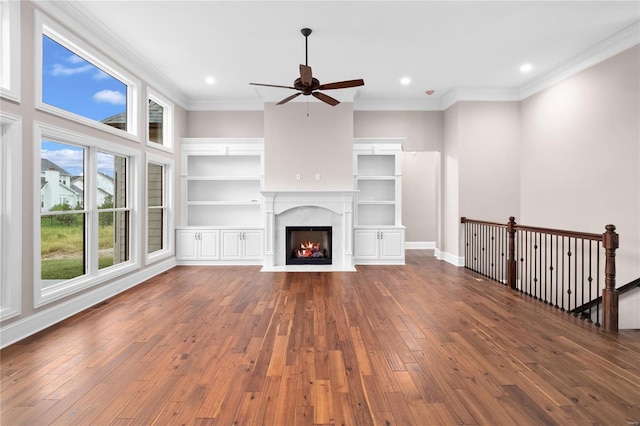 unfurnished living room with built in shelves, ornamental molding, ceiling fan, and dark hardwood / wood-style flooring