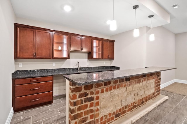 kitchen with dark stone counters, tile flooring, sink, and pendant lighting