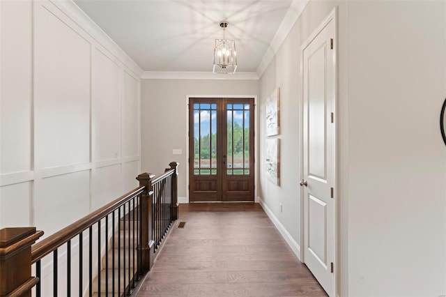 foyer with ornamental molding, dark hardwood / wood-style floors, a notable chandelier, and french doors