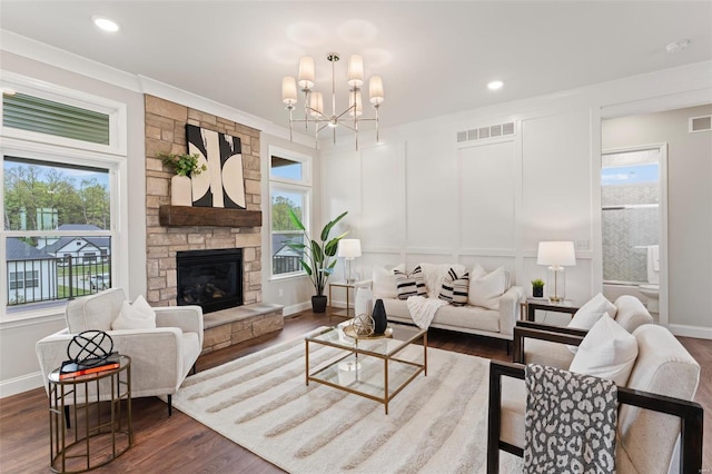 living room with an inviting chandelier, crown molding, a fireplace, and dark hardwood / wood-style floors