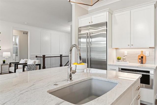 kitchen featuring light stone countertops, appliances with stainless steel finishes, sink, and white cabinets