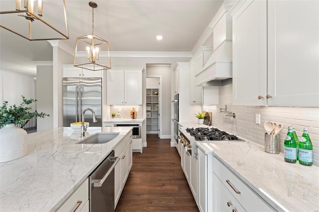 kitchen with pendant lighting, sink, stainless steel appliances, custom range hood, and white cabinets