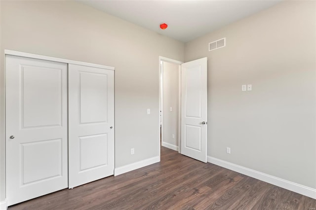 unfurnished bedroom featuring dark hardwood / wood-style floors and a closet