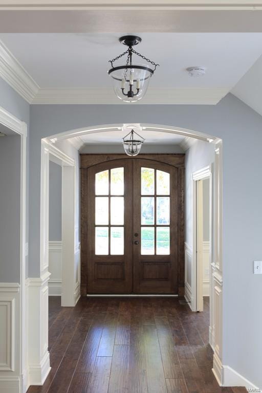 foyer entrance featuring french doors, crown molding, an inviting chandelier, and dark hardwood / wood-style flooring