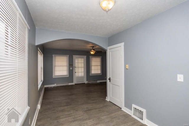 hall featuring a baseboard heating unit, dark wood-type flooring, and a textured ceiling