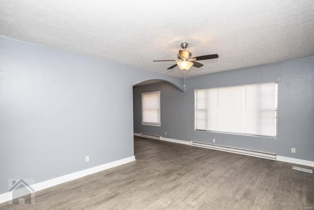 unfurnished room featuring a baseboard heating unit, dark wood-type flooring, ceiling fan, and a textured ceiling