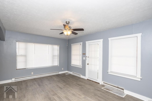 empty room featuring ceiling fan, a baseboard heating unit, and dark wood-type flooring