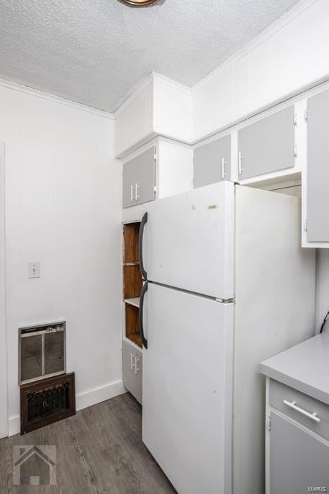 kitchen featuring dark wood-type flooring, white fridge, white cabinets, and a textured ceiling