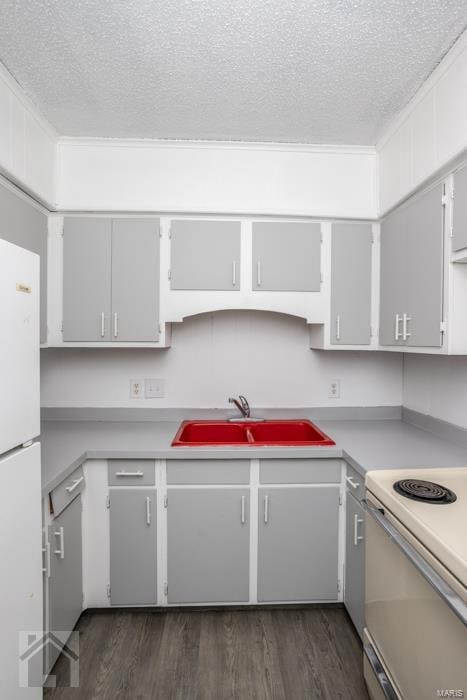 kitchen with dark hardwood / wood-style flooring, white appliances, sink, and a textured ceiling