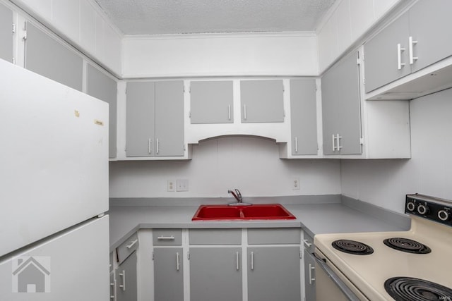 kitchen featuring a textured ceiling, sink, white refrigerator, and range