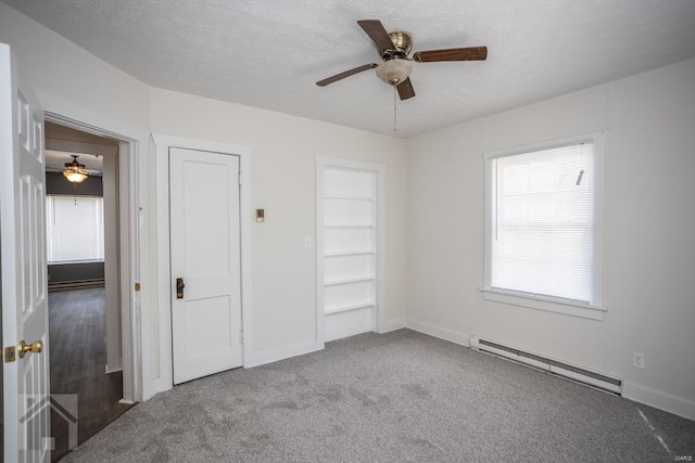 unfurnished bedroom with a textured ceiling, ceiling fan, light carpet, and baseboard heating