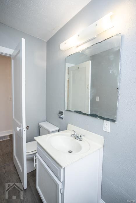 bathroom with vanity, toilet, and a textured ceiling