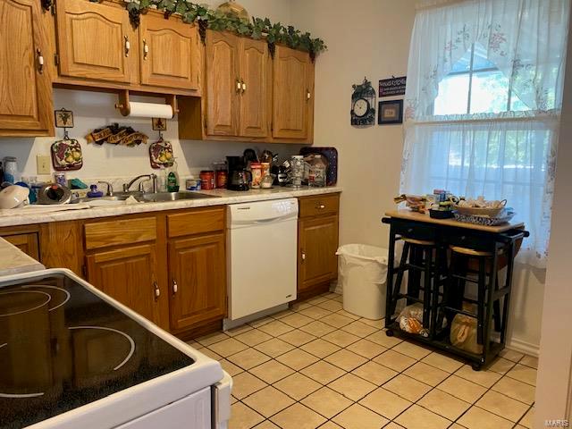 kitchen featuring white dishwasher, range, sink, and light tile floors