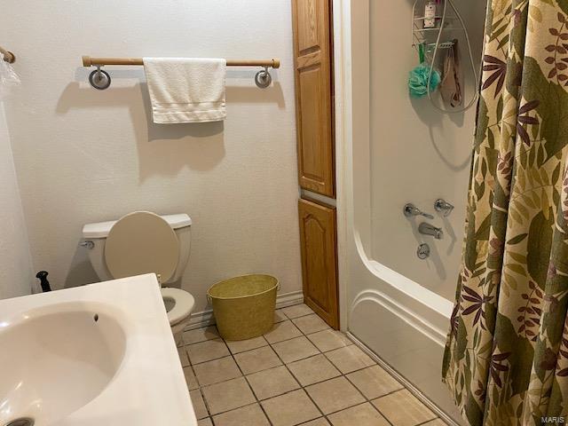 bathroom featuring tile flooring, toilet, and shower / tub combo with curtain