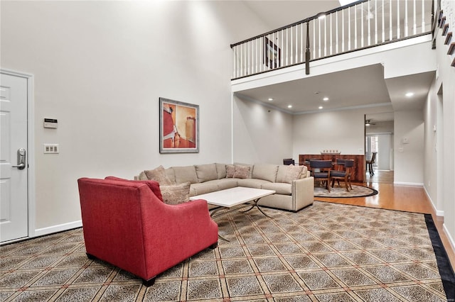 living room featuring a towering ceiling, hardwood / wood-style floors, and ornamental molding