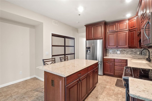 kitchen featuring a kitchen island, appliances with stainless steel finishes, backsplash, sink, and light tile floors