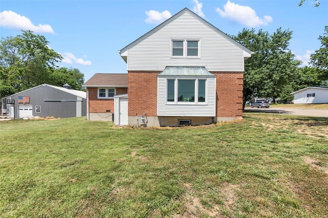 back of property with a garage, a lawn, and an outbuilding