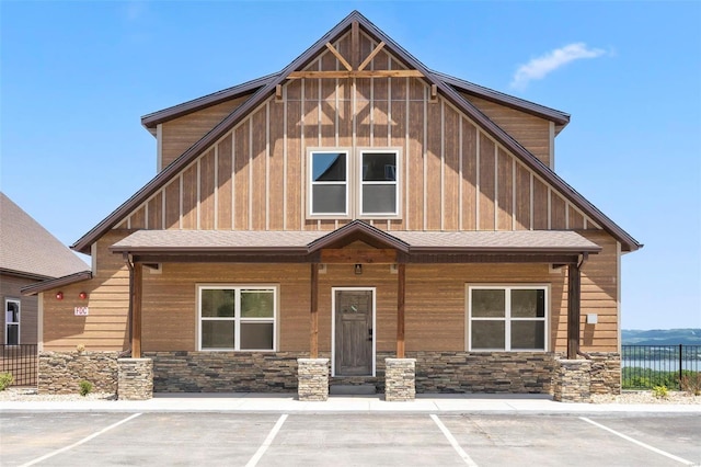 view of front of home with board and batten siding, stone siding, and fence