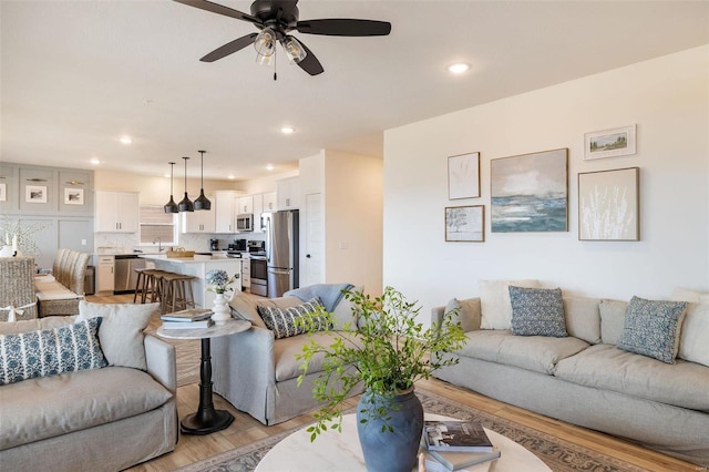 living area with light wood-type flooring, ceiling fan, and recessed lighting