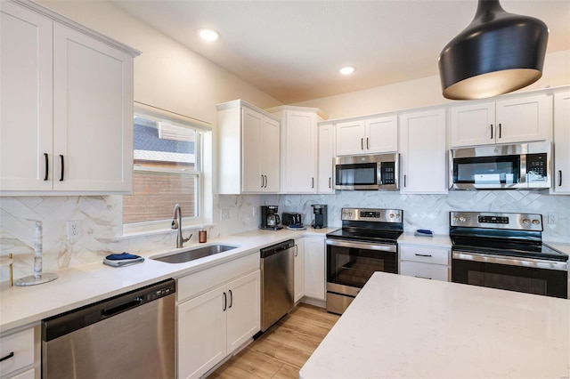 kitchen featuring light wood-type flooring, white cabinetry, appliances with stainless steel finishes, and a sink