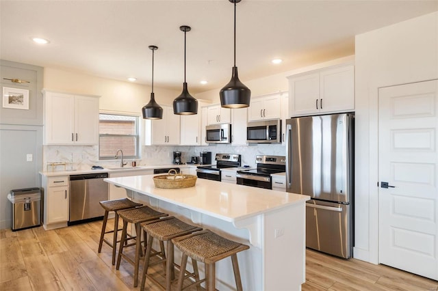 kitchen featuring stainless steel appliances, a center island, light countertops, and white cabinetry