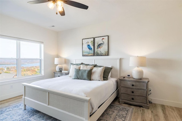 bedroom featuring ceiling fan, light wood-type flooring, visible vents, and baseboards