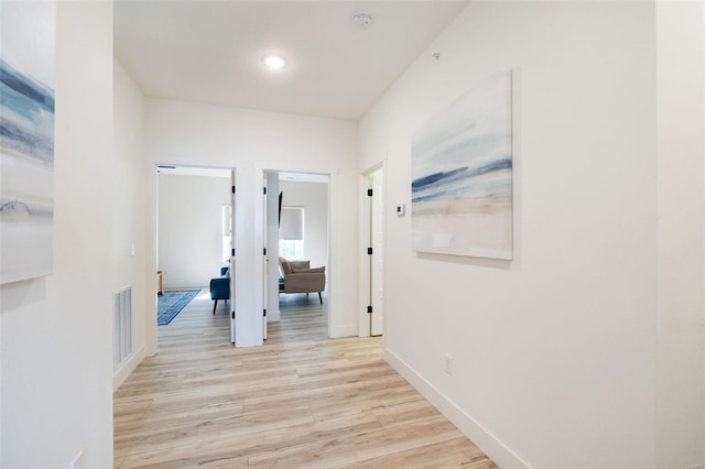 corridor featuring light wood-style floors, visible vents, and baseboards